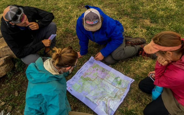a group of students examine a map that is spread out on the ground
